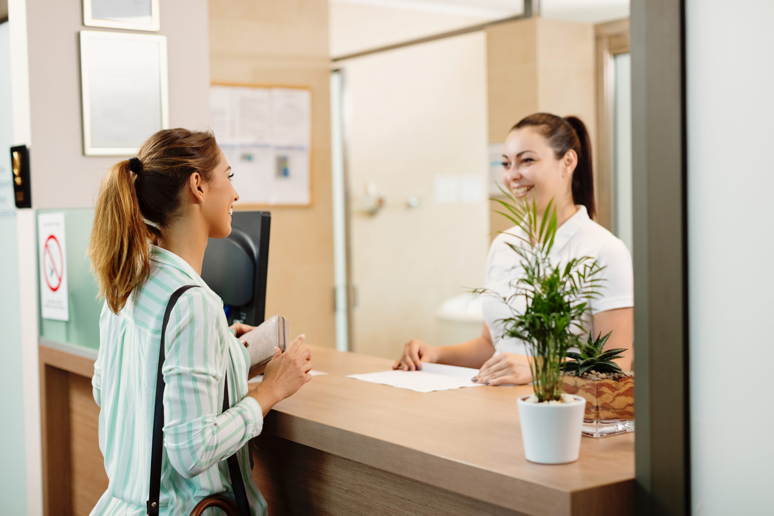 happy woman talking receptionist while arriving spa scaled