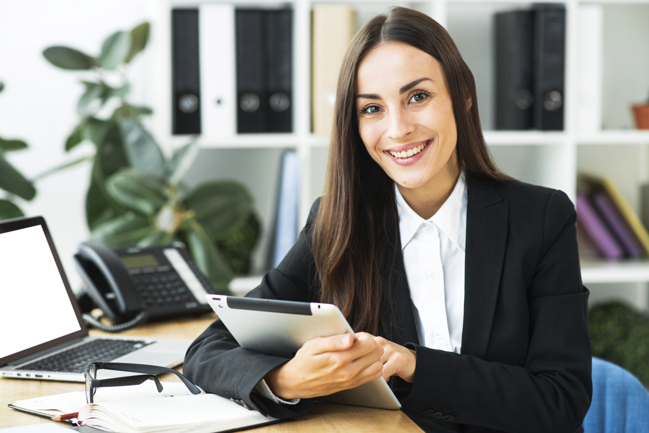 portrait young businesswoman sitting desk holding digital tablet her hand scaled