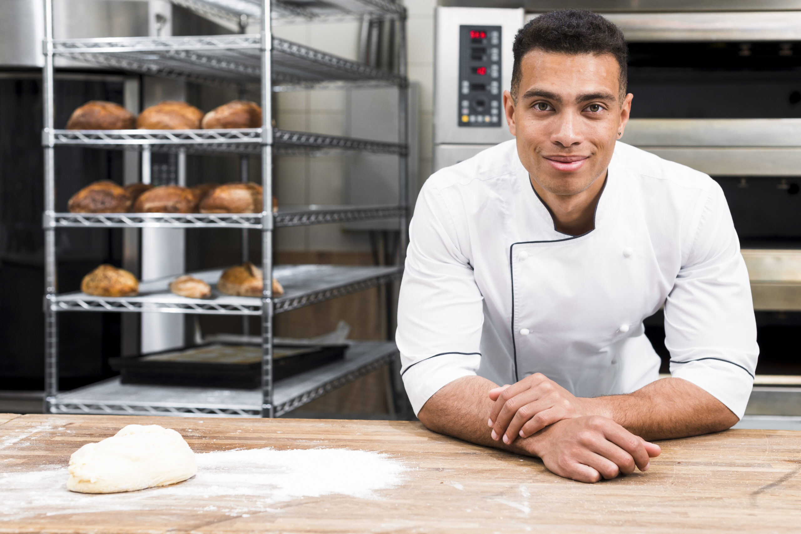 male baker standing table with dough bakery scaled