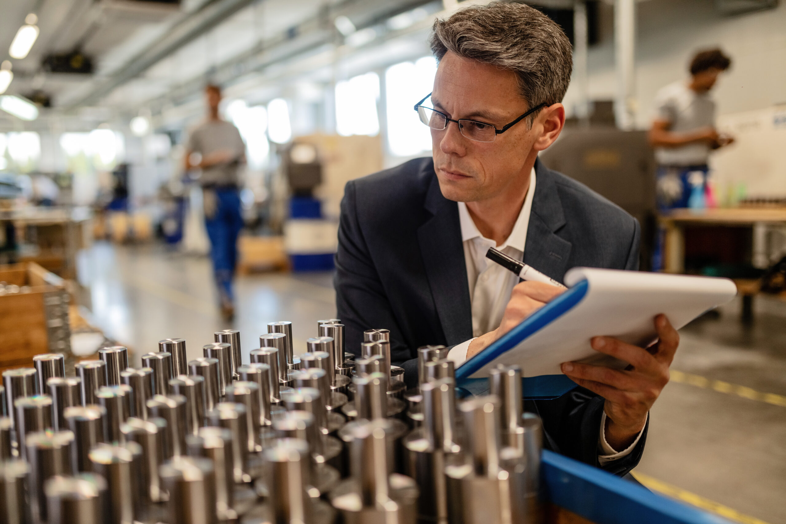 quality control inspector writing reports while analzying manufactured steel rod cylinders industrial building scaled
