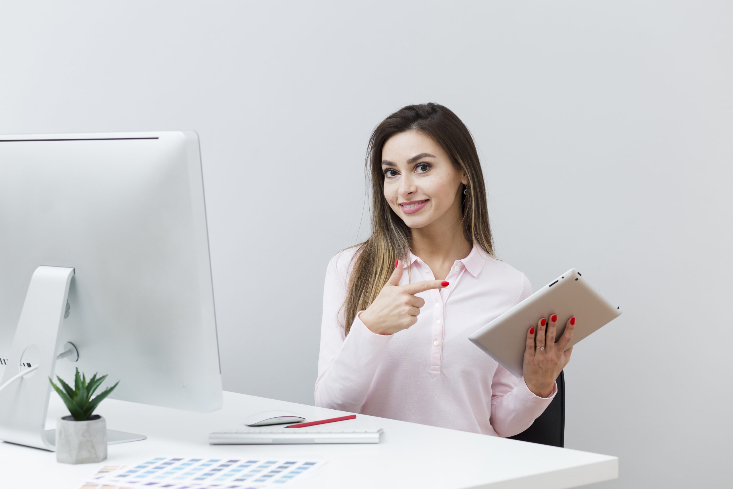 smiley woman desk pointing tablet scaled