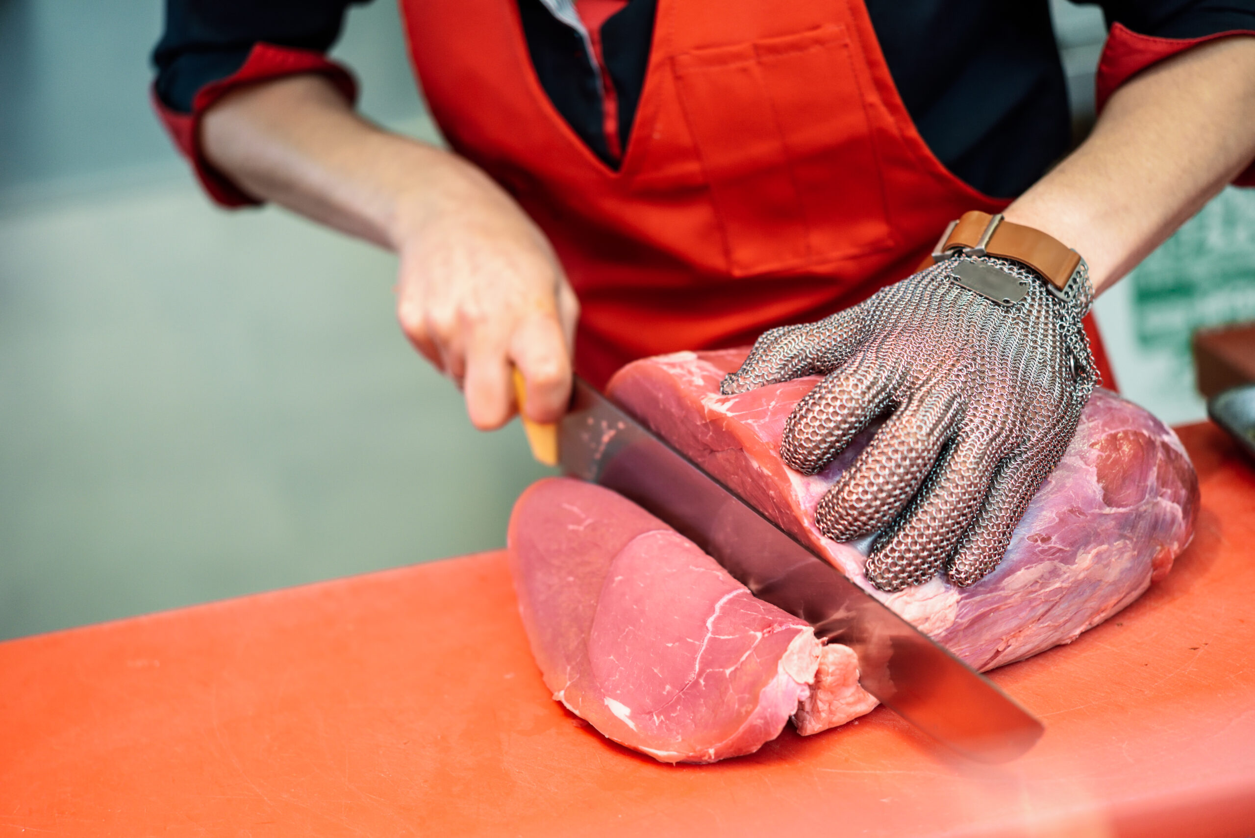 woman cutting fresh meat butcher shop with metal safety mesh glove scaled